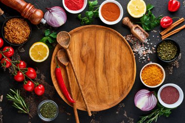 Siyah taştan bir arka planda Hint baharatları ve otları. Bir kaşıkta zerdeçal, dereotu, paprika, tarçın, safran, fesleğen ve biberiye. Üst Manzara. Model.