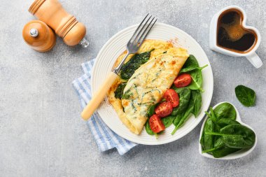Ispanaklı omlet, kiraz domatesli ve biberli omlet beyaz tabakta, açık gri arkaplanda. Sağlıklı kahvaltı konsepti. Üst görünüm.
