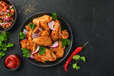 Izgara tavuk kanadı ya da baharatlı kızarmış bbq ve siyah tabakta domates sosu. Kopyalama alanı olan üst görünüm.