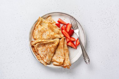 Krem peynirli krep ve güzel beyaz seramik tabakta taze çilek. Mesaj ya da tarif için boşluk. Üst görünüm