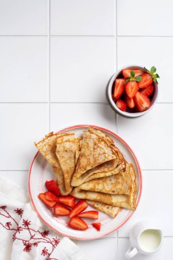 Krem peynirli krep ve güzel beyaz seramik tabakta taze çilek. Mesaj ya da tarif için boşluk. Üst görünüm.