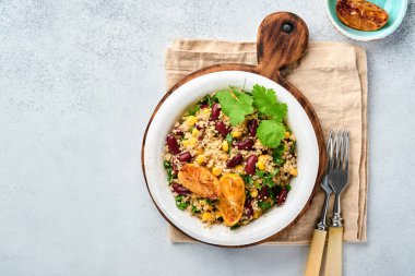 Meksika siyah fasulyeli kinoa salatası ve karamelize edilmiş limon açık gri beton arka planda eski moda kil kasede. Geleneksel Meksika mutfağı. Üst görünüm, modelle.