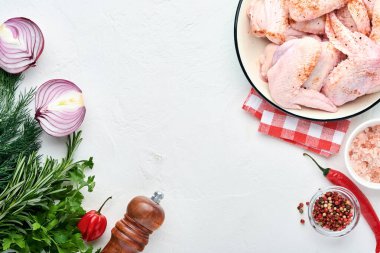 Beyaz bir kasede çiğ tavuk kanadı. Baharat ve malzemelerle hafif kayrak, taş ya da beton arka planda yemek pişirmek için. Kopyalama alanı olan üst görünüm. Model.