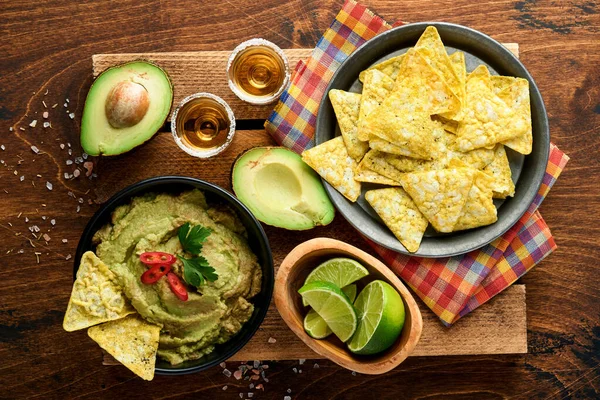 stock image Guacamole. Traditional latinamerican Mexican dip sauce in a black bowl with avocado and ingredients and corn nachos. Avocado spread. Top view. Copy space.