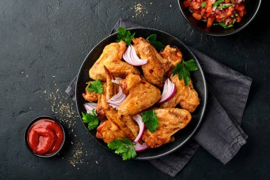 Izgara tavuk kanadı ya da baharatlı kızarmış bbq ve siyah tabakta domates sosu. Kopyalama alanı olan üst görünüm.