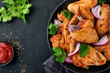 Izgara tavuk kanadı ya da baharatlı kızarmış bbq ve siyah tabakta domates sosu. Kopyalama alanı olan üst görünüm.