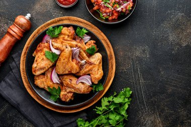 Izgara tavuk kanadı ya da baharatlı kızarmış bbq ve siyah tabakta domates sosu. Kopyalama alanı olan üst görünüm.