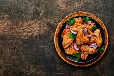 Izgara tavuk kanadı ya da baharatlı kızarmış bbq ve siyah tabakta domates sosu. Kopyalama alanı olan üst görünüm.