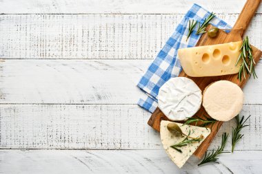 Set ya da çeşitli peynirler. Baharatlı suluguni, camembert, mavi peynir, parmesan, maasdam, biberiyeli brie peyniri ve biber. Üst Manzara. Beyaz ahşap arka planda. Boş kopyalama alanı.