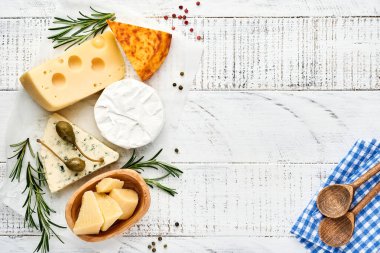 Set ya da çeşitli peynirler. Baharatlı suluguni, camembert, mavi peynir, parmesan, maasdam, biberiyeli brie peyniri ve biber. Üst Manzara. Beyaz ahşap arka planda. Boş kopyalama alanı.