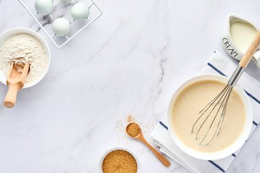 Kahvaltı ya da Maslenitsa için ev krepleri için hamur hazırlama. Masadaki malzemeler - buğday unu, yumurta, tereyağı, şeker, tuz, süt. Adım adım tarif et. Metin için yeri olan üst görünüm.