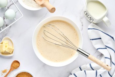 Kahvaltı ya da Maslenitsa için ev krepleri için hamur hazırlama. Masadaki malzemeler - buğday unu, yumurta, tereyağı, şeker, tuz, süt. Adım adım tarif et. Metin için yeri olan üst görünüm.