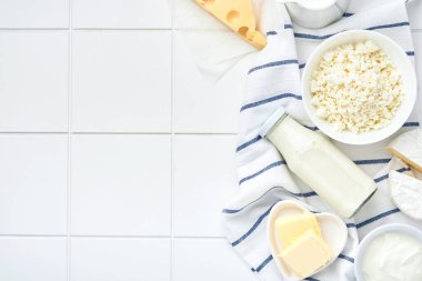 Beyaz masa arkasında bir bardak süt, süzme peynir, ricotta, ekşi krema, peynir, camembert ve tereyağı. Farklı süt ürünleri. Süt konsepti. Kopyalama alanı olan üst görünüm. Model.