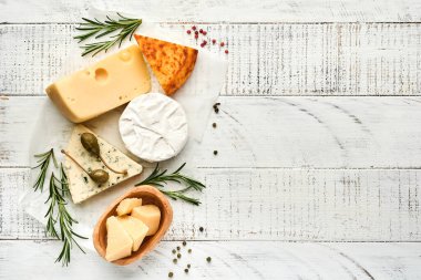 Set ya da çeşitli peynirler. Baharatlı suluguni, camembert, mavi peynir, parmesan, maasdam, biberiyeli brie peyniri ve biber. Üst Manzara. Beyaz ahşap arka planda. Boş kopyalama alanı.