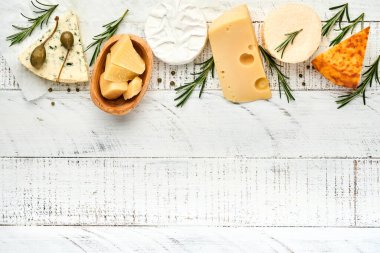 Set ya da çeşitli peynirler. Baharatlı suluguni, camembert, mavi peynir, parmesan, maasdam, biberiyeli brie peyniri ve biber. Üst Manzara. Beyaz ahşap arka planda. Boş kopyalama alanı.