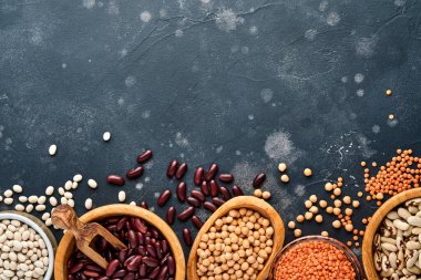 Legumes, kırmızı mercimek, nohut, kırmızı ve beyaz fasulye çeşitleri koyu siyah masada farklı kaselerde. Kilo vermek ve kolesterol kavramına karşı savaşmak için diyet. Kopyalama alanı olan üst görünüm.
