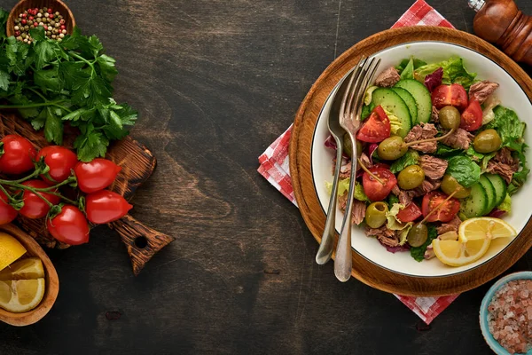 Taze sebzeli, zeytinli, kapari ve limonlu ton balığı salatası eski ahşap arka planda servis edilir. Kopyalama alanı olan üst görünüm.