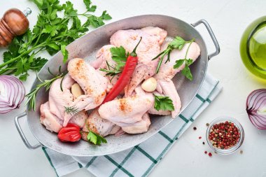 Beyaz bir kasede çiğ tavuk kanadı. Baharat ve malzemelerle hafif kayrak, taş ya da beton arka planda yemek pişirmek için. Kopyalama alanı olan üst görünüm. Model.