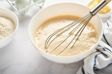 Kahvaltı ya da Maslenitsa için ev krepleri için hamur hazırlama. Buğday unu, yumurta, tereyağı, şeker, tuz, süt. Adım adım tarif et. Seçici odak.