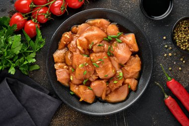 Teriyaki soya sosunda marine edilmiş çiğ tavuk eti, soğan ve biber siyah bir tabakta, taş, beton arka planda. Kopyalama alanı olan üst görünüm.