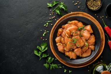 Teriyaki soya sosunda marine edilmiş çiğ tavuk eti, soğan ve biber siyah bir tabakta, taş, beton arka planda. Kopyalama alanı olan üst görünüm.