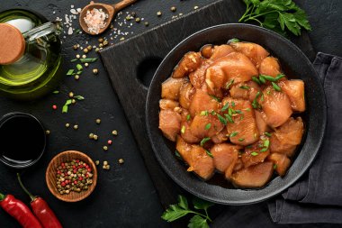 Teriyaki soya sosunda marine edilmiş çiğ tavuk eti, soğan ve biber siyah bir tabakta, taş, beton arka planda. Kopyalama alanı olan üst görünüm.