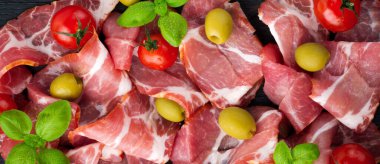 Kurutulmuş et, vişneli domates, fesleğen ve siyah arka planda zeytin. Seçici odaklanma. Üst görüş. Boşluğu kopyala.