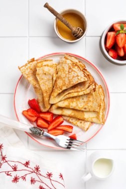 Krem peynirli krep ve güzel beyaz seramik tabakta taze çilek. Mesaj ya da tarif için boşluk. Üst görünüm