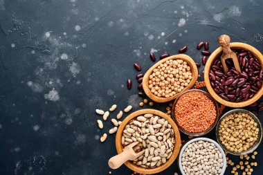 Legumes, kırmızı mercimek, nohut, kırmızı ve beyaz fasulye çeşitleri koyu siyah masada farklı kaselerde. Kilo vermek ve kolesterol kavramına karşı savaşmak için diyet. Kopyalama alanı olan üst görünüm.