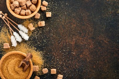 Beyaz şeker, kamış şeker küpleri, koyu kahverengi masa çimento zemininde bambu kasesinde karamel. Farklı şeker çeşitleri vardı. Üst görünüm veya düz uzanma.