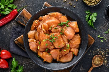 Teriyaki soya sosunda marine edilmiş çiğ tavuk eti, soğan ve biber siyah bir tabakta, taş, beton arka planda. Kopyalama alanı olan üst görünüm.