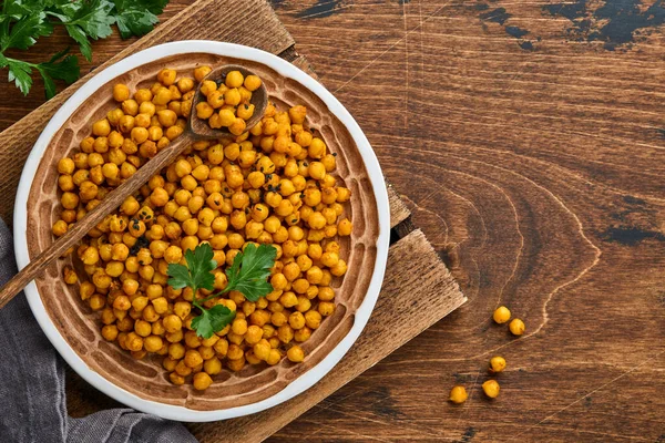 Fried chickpeas with turmeric in ceramic plate on an old wooden table background. Roasted spicy chickpeas or Indian chana or chole, popular snack recipe. Top view. — Stock Photo, Image