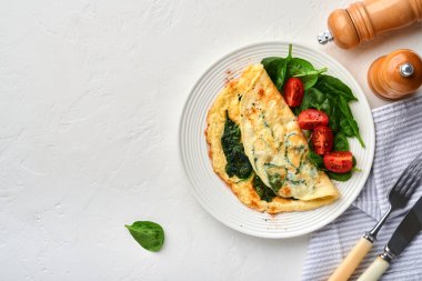 Ispanaklı omlet, kiraz domatesli ve biberli omlet beyaz bir tabakta, beyaz arka planda. Üst görünüm.