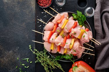 Ahşap tahtada çiğ şiş kebap, baharatlar, otlar ve koyu gri arka planda sebzeler. Gulaş ya da şiş kebap için mangal malzemesi. Üst Manzara. Boş kopyalama alanı.