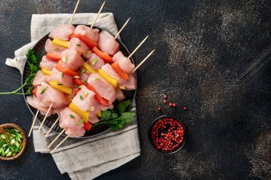 Ahşap tahtada çiğ şiş kebap, baharatlar, otlar ve koyu gri arka planda sebzeler. Gulaş ya da şiş kebap için mangal malzemesi. Üst Manzara. Boş kopyalama alanı.