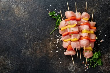 Ahşap tahtada çiğ şiş kebap, baharatlar, otlar ve koyu gri arka planda sebzeler. Gulaş ya da şiş kebap için mangal malzemesi. Üst Manzara. Boş kopyalama alanı.