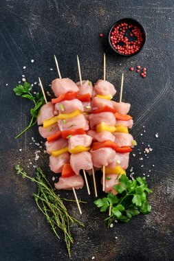 Ahşap tahtada çiğ şiş kebap, baharatlar, otlar ve koyu gri arka planda sebzeler. Gulaş ya da şiş kebap için mangal malzemesi. Üst Manzara. Boş kopyalama alanı.