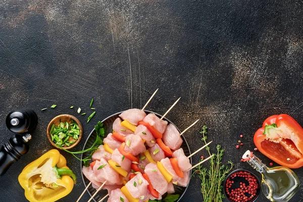 Ahşap tahtada çiğ şiş kebap, baharatlar, otlar ve koyu gri arka planda sebzeler. Gulaş ya da şiş kebap için mangal malzemesi. Üst Manzara. Boş kopyalama alanı.