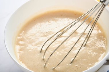 Kahvaltı ya da Maslenitsa için ev krepleri için hamur hazırlama. Buğday unu, yumurta, tereyağı, şeker, tuz, süt. Adım adım tarif et. Seçici odak.