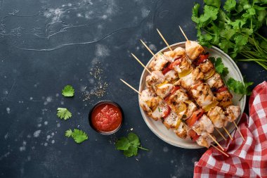 Tavuklu şiş kebap ya da tahta tahtada şiş kebap, baharatlar, otlar ve koyu gri arka planda sebzeler. Gulaş ya da şiş kebap için mangal malzemesi. Üst Manzara. Boş kopyalama alanı.