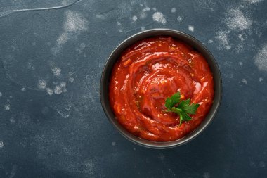 Siyah bir kâse içinde domates ketçap baharatlı sos. Baharatlar ve taze domatesler koyu bir tahta, taş ya da beton arka planda. Kopyalama alanı olan üst görünüm.