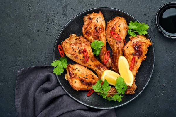 Izgara tavuk butları ya da bacaklar ya da baharatlı kızarmış bbq ve siyah tabakta domates sosu. Kopyalama alanı olan üst görünüm.