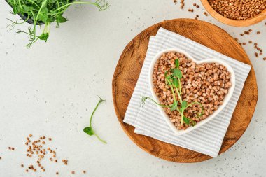 Eski beyaz ahşap arka planda, kalp şeklinde kase içinde kaynamış karabuğday lapası. Sağlıklı beslenme için glütensiz antik tahıl. Üst Manzara. Boşluğu kopyala.