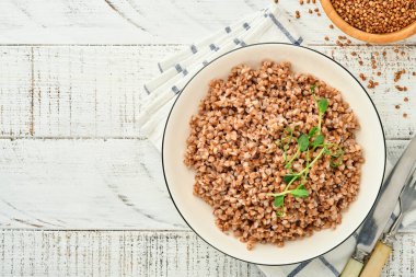 Eski beyaz ahşap arka planda maydanoz yaprağı ve tereyağlı karabuğday lapası. Ev yapımı yemek. Sağlıklı beslenme için glütensiz antik tahıl. Üst Manzara. Boşluğu kopyala.