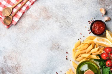 Makarna arka planı. Makarna rigati, domates ketçap sosu, zeytinyağı, baharatlar, maydanoz ve açık gri bir masa üzerinde taze domatesler. Yemek pişirme geçmişi. Kopyalama alanı olan üst görünüm.