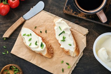 Yumuşak peynirli sandviç, yeşil soğanlı ve koyu ahşap arka planda ekmek. Ricotta sandviçi ve kahveyle basit bir kahvaltı. Metin için en üst görünüm kopyalama alanı.