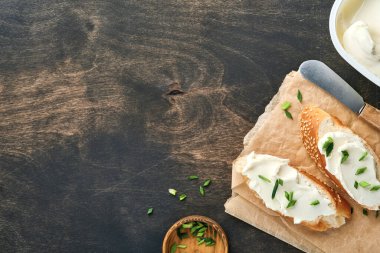 Yumuşak peynirli sandviç, yeşil soğanlı ve koyu ahşap arka planda ekmek. Ricotta sandviçi ve kahveyle basit bir kahvaltı. Metin için en üst görünüm kopyalama alanı.