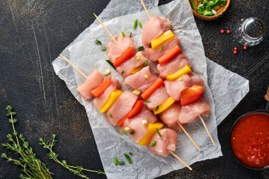 Ahşap tahtada çiğ şiş kebap, baharatlar, otlar ve koyu gri arka planda sebzeler. Gulaş ya da şiş kebap için mangal malzemesi. Üst Manzara. Boş kopyalama alanı.