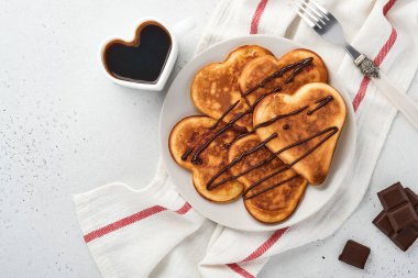 Gri seramik tabakta çikolata soslu gözleme ve gri beton arka planda bir fincan kahve. Sevgililer Günü kahvaltısı için masayı hazırla. Üst görünüm kopyalama alanı.