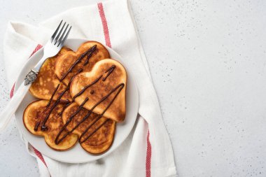 Gri seramik tabakta çikolata soslu gözleme ve gri beton arka planda bir fincan kahve. Sevgililer Günü kahvaltısı için masayı hazırla. Üst görünüm kopyalama alanı.
